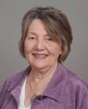 A woman in purple jacket smiling for the camera.