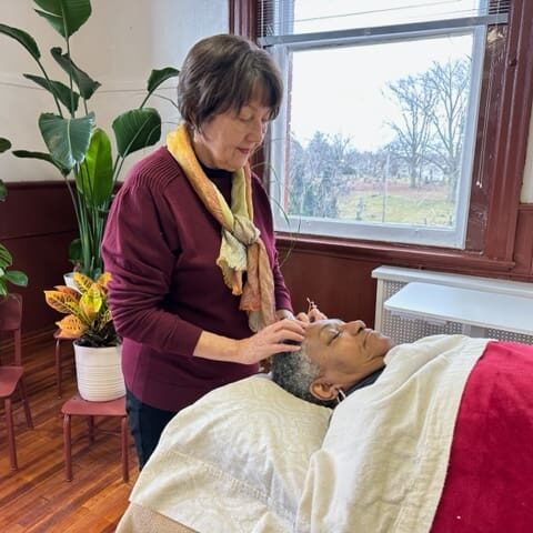 A woman is standing in front of a bed