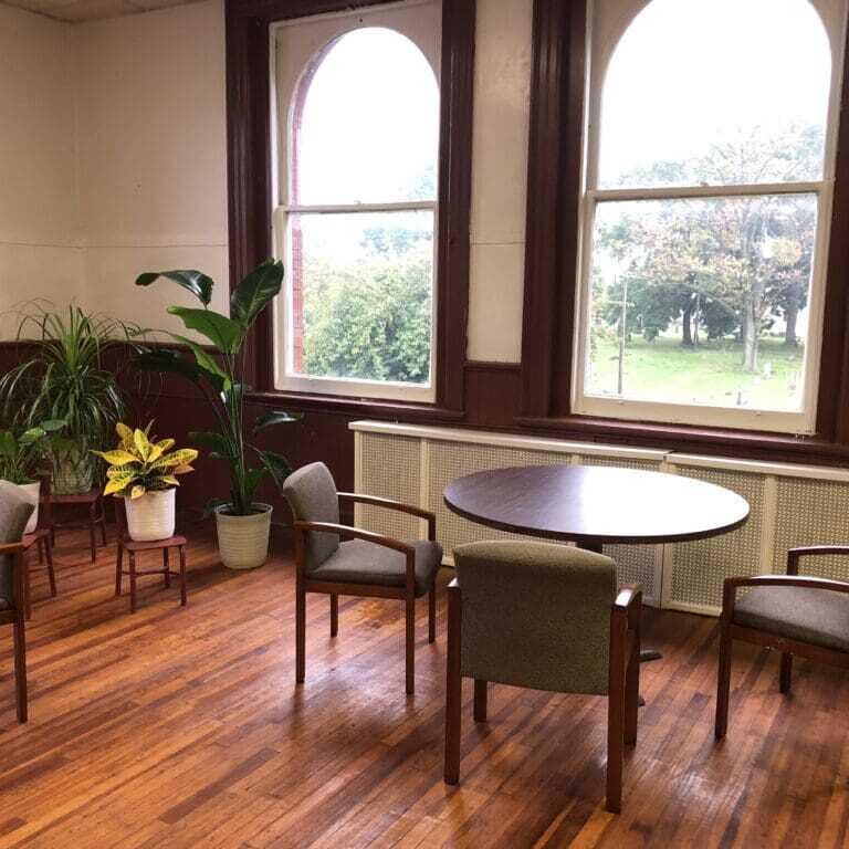 A room with four chairs and two tables.